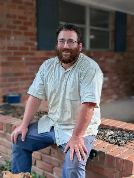 Justin Marks, owner of Giving Tree Lawn Care, resting on a brick porch step at the end of a work day.